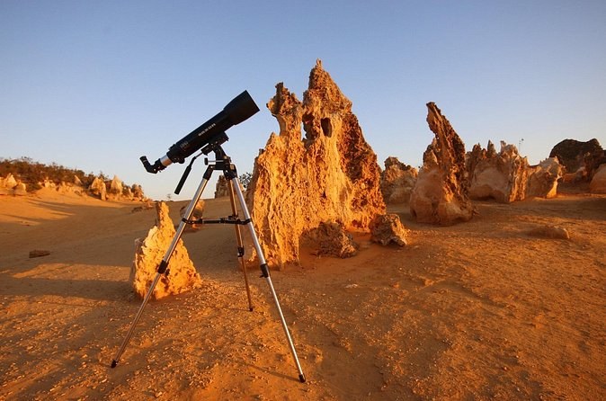 A telescope set up among the pillars in the last of the evening light
